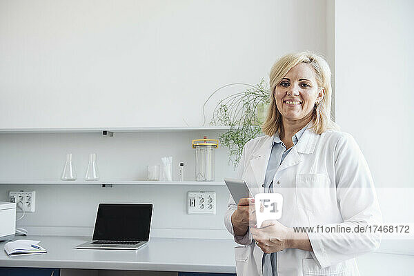 Blond scientist holding tablet PC in laboratory