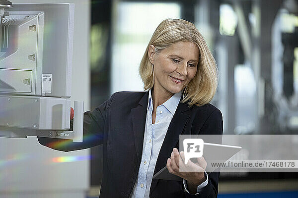 Blond businesswoman with digital tablet working in factory
