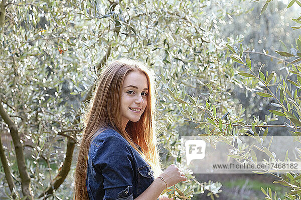 Smiling woman holding branch of tree at countryside
