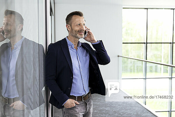 Mature male professional talking on mobile phone in corridor