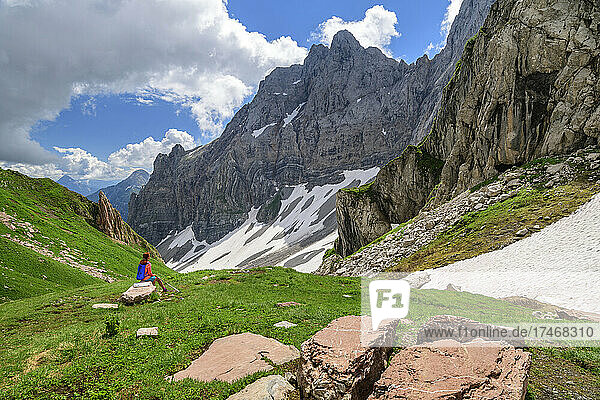 Wanderin sitzt auf einem Felsen und blickt auf die Berge in Kärnten  Österreich
