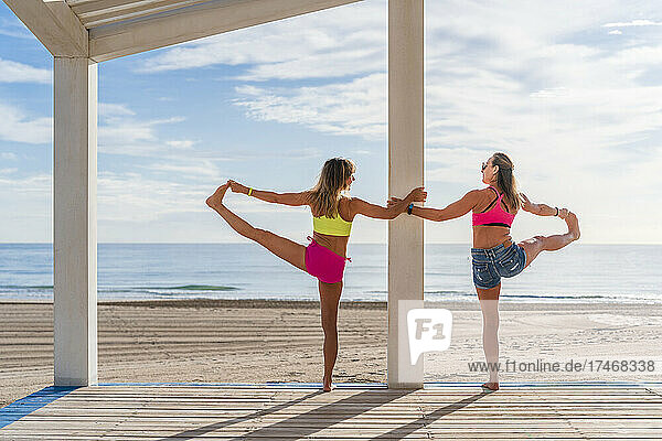 Mature sportswomen balancing on one leg while practicing at beach
