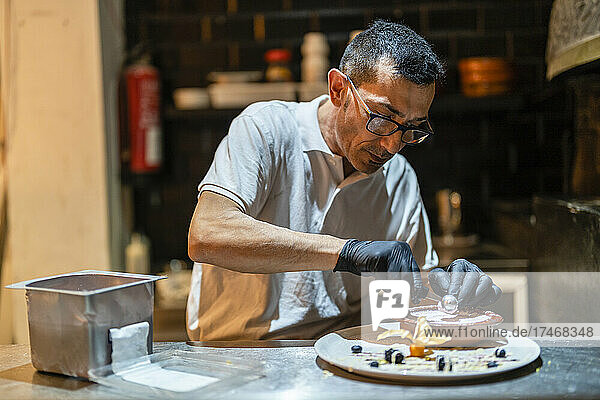 Concentrated chef decorating dessert in kitchen