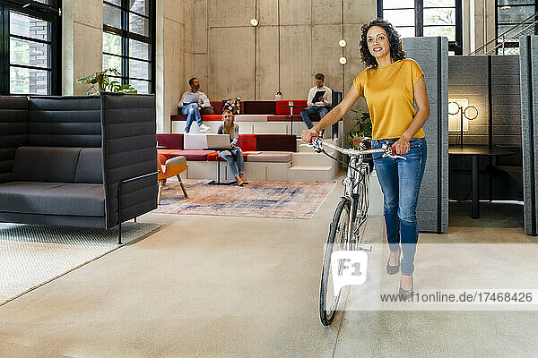 Businesswoman with bicycle walking in office