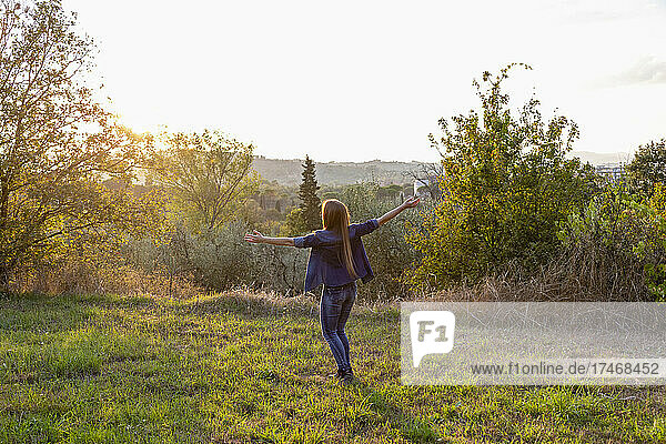 Carefree woman enjoying sunset at countryside