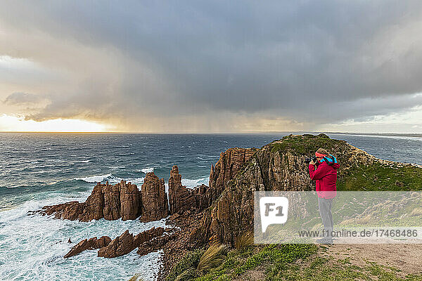 Female tourist taking photos from Pinnacles Lookout at cloudy sunset