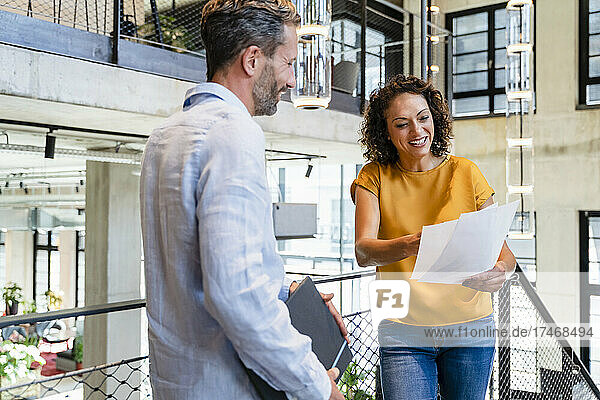 Businesswoman discussing over document with colleague at office