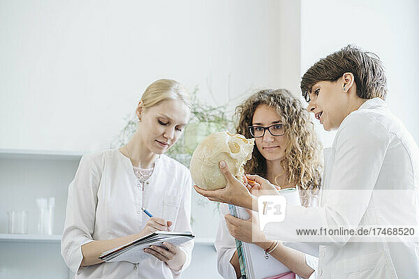 Researcher explaining over human skull to colleagues in laboratory