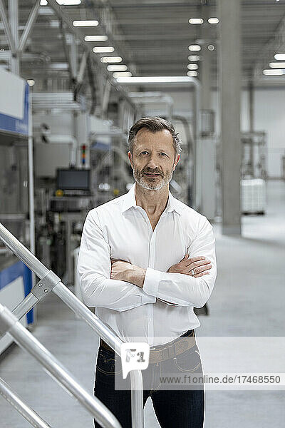 Confident male professional standing with arms crossed in factory