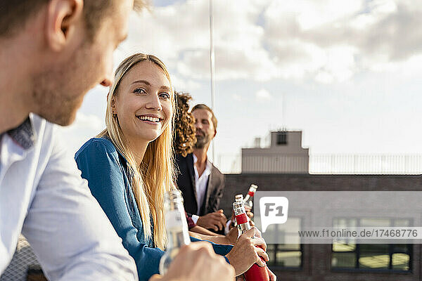 Young businesswoman having drink with colleagues on rooftop