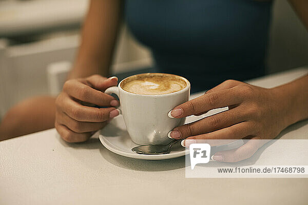 Young woman with manicured nails having coffee at cafe