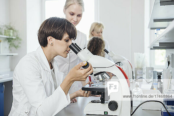 Scientist checking sample through microscope in laboratory
