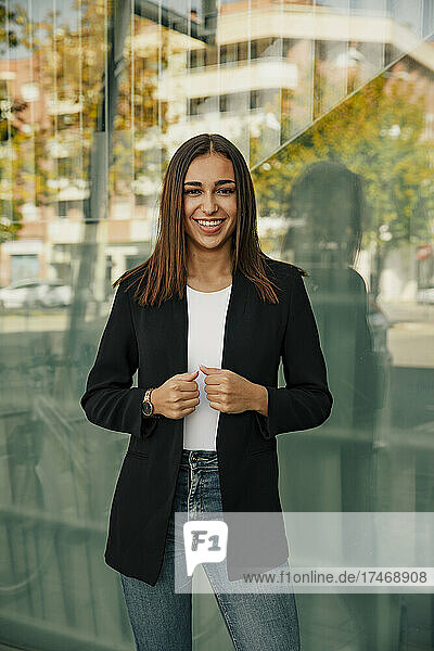 Lächelnde Geschäftsfrau in Jacke vor Glas