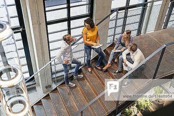 Businesswoman discussing with colleagues on staircase
