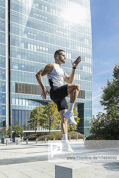 Sportsman exercising in front of building during sunny day