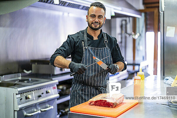 Chef sharpening knife for cutting meat in commercial kitchen