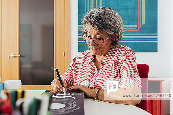 Senior woman painting on canvas at home