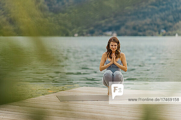 Woman meditating while doing yoga on jetty