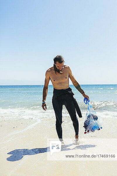 Male environmentalist with mesh bag at beach