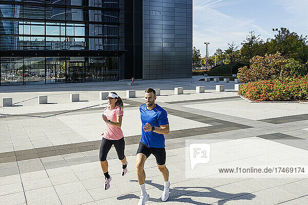 Male and female athlete running during sunny day