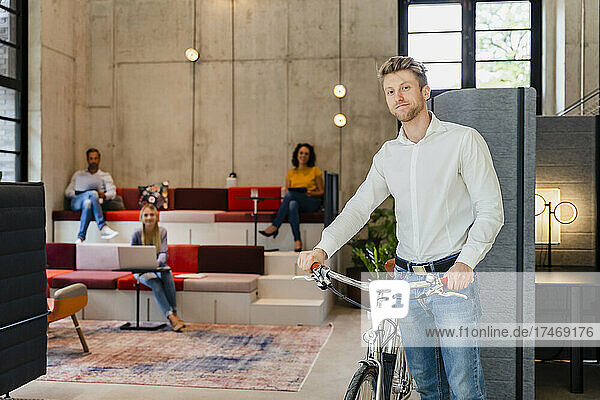 Young businessman with bicycle at coworking office