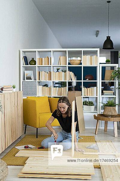 Woman with screwdriver assembling furniture at home