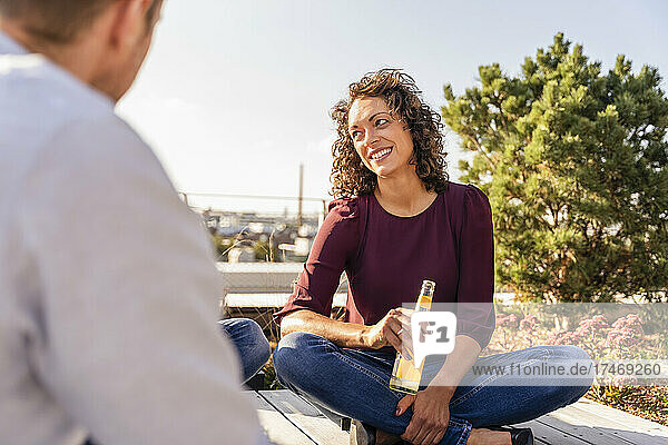 Lächelnde Geschäftsfrau trinkt mit Kollegen auf dem Dach