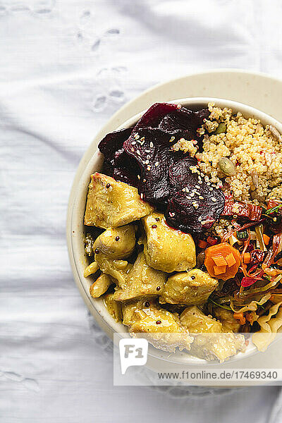 Marinated chicken with quinoa and vegetables in bowl on table