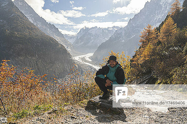 Man squatting in front of Mer de Glace glacier on sunny day  Chamonix  France