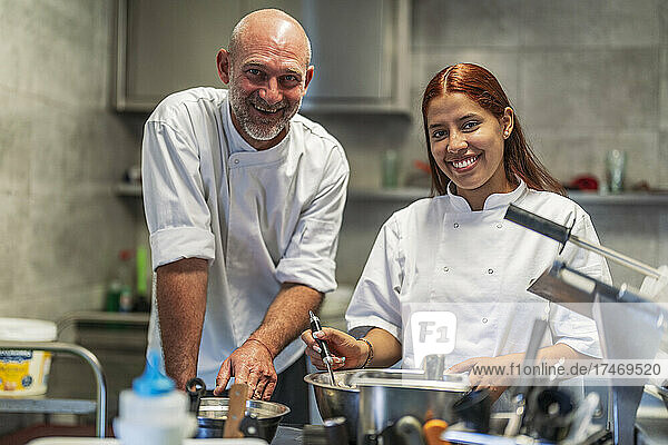 Smiling male and female chefs working in kitchen
