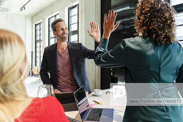 Businessman giving high-five to coworker at desk
