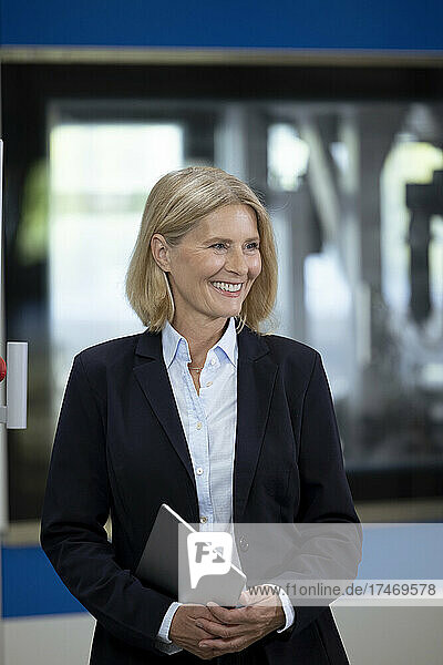 Mature businesswoman with digital tablet smiling in industry