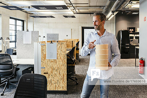 Businessman with stack of lunch boxes in office