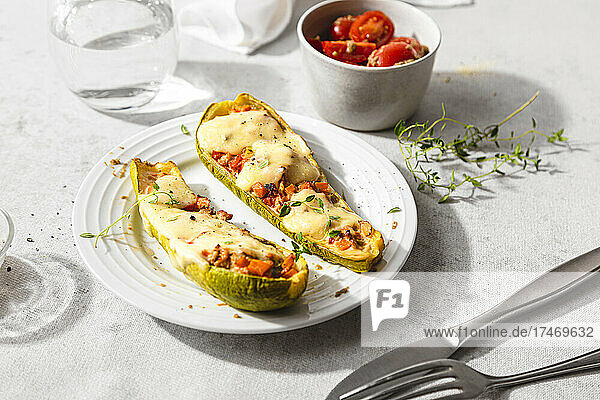 Stuffed zucchini with cheese by cherry tomatoes on table
