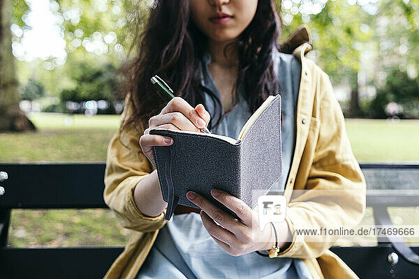 Junge Frau schreibt Tagebuch im Park