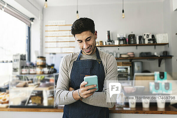 Waiter using smart phone in coffee shop