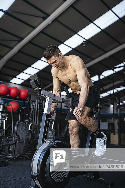 Motivated male athlete exercising on exercise bike in gym