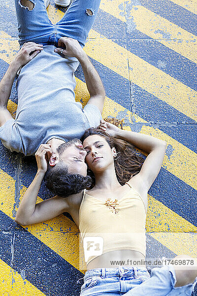 Couple lying together on yellow striped footpath