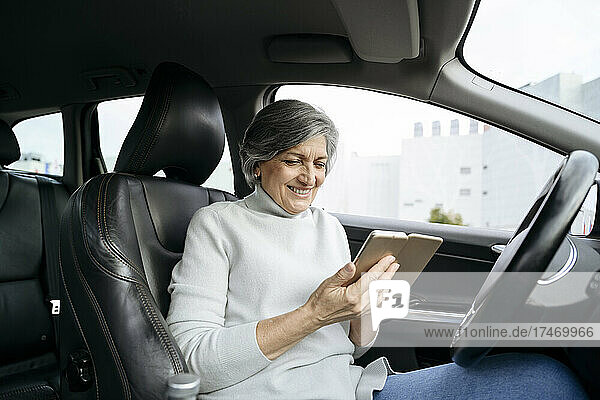 Smiling woman using smart phone in car