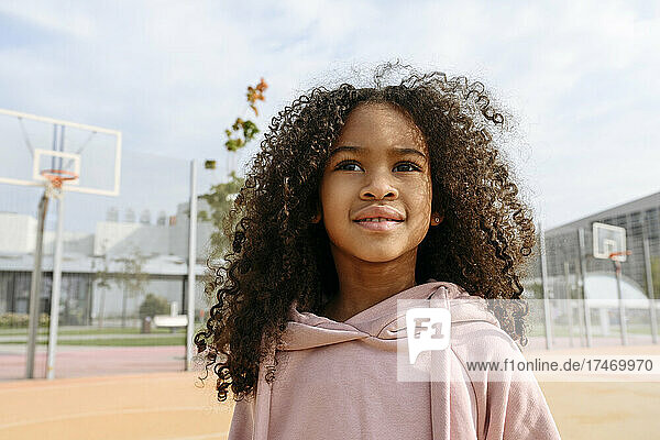 Girl with brown curly hair at sports field