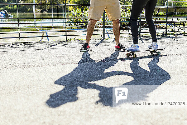 Girl learning skateboarding with friend in park