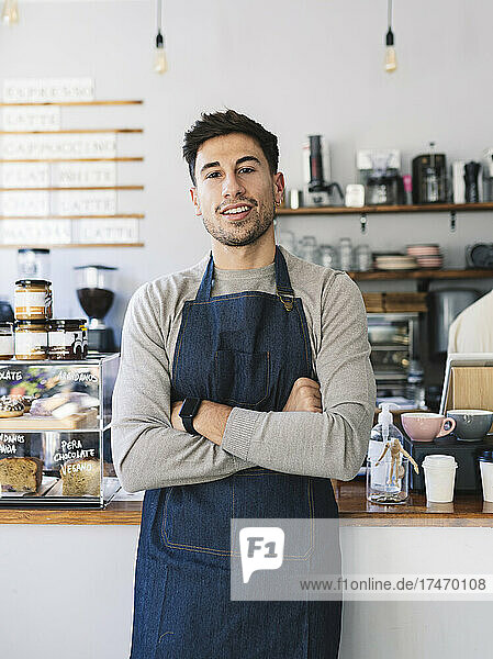 Smiling owner with arms crossed in coffee shop