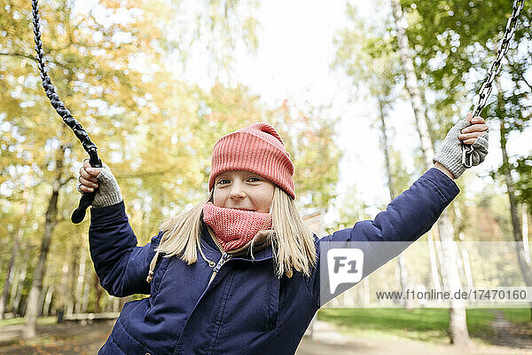 Blond girl holding rope while playing in park
