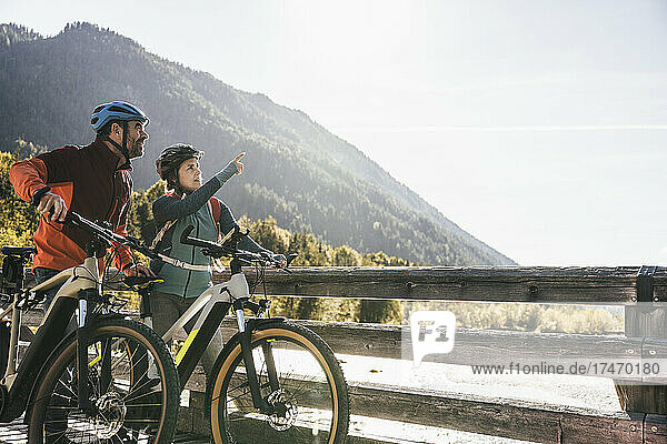 Couple with bicycles on bridge looking away