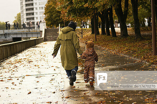 Playful mother and daughter running in autumn park