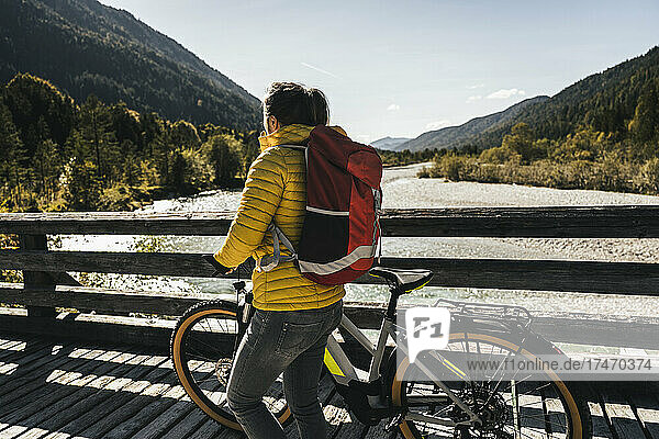 Woman with backpack and mountain bike on bridge