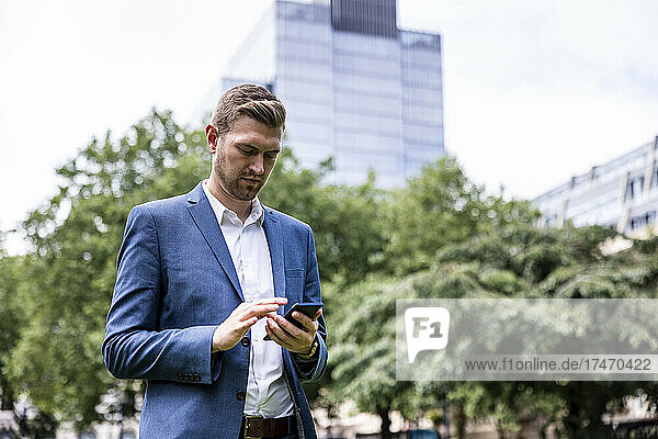Young businessman using smart phone in city