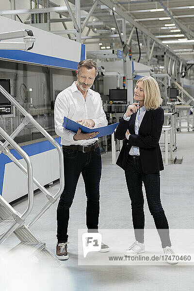 Businessman discussing strategy with female colleague in factory