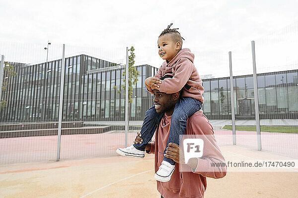 Man carrying boy on shoulders at sports field