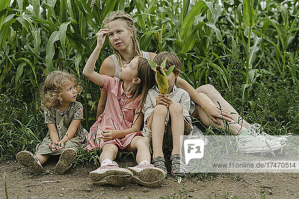 Mutter sitzt mit Sohn und Töchtern im Maisfeld